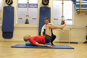 Client being assisted on a Pilates mat