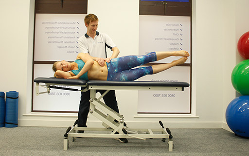 Pilates instructor assisting a client on an exercise bed 
