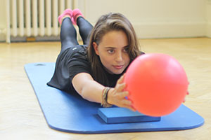 client using pilates ball on mat